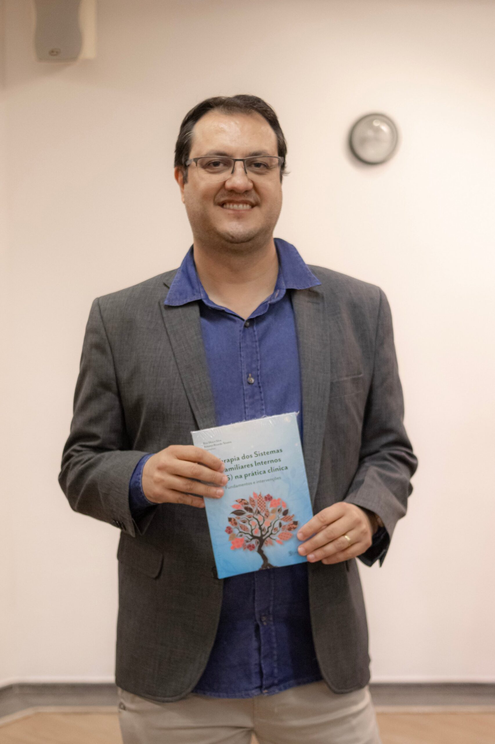 Dr. Marcelo Viana, psiquiatra e terapeuta de EMDR, com o livro sobre IFS